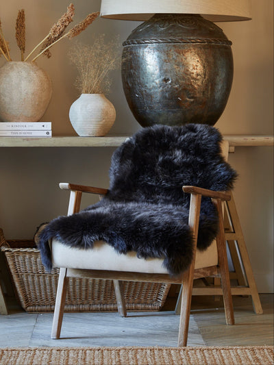 Chair with a black fur cover in front of a wooden table with decorative items.