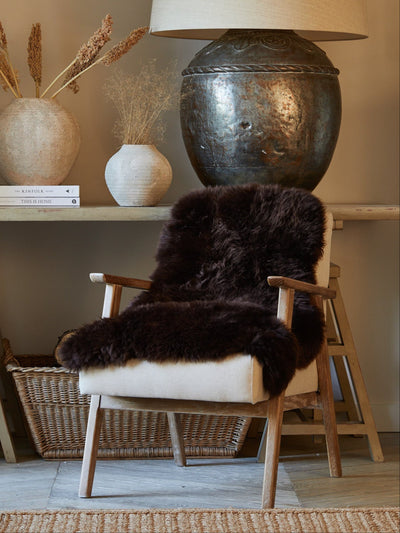 Chair with a fur throw, table with decorative items, and lamp in a room setting.