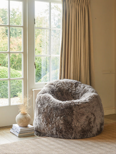 sheepskin bean bag chair in a room with large windows and curtains.