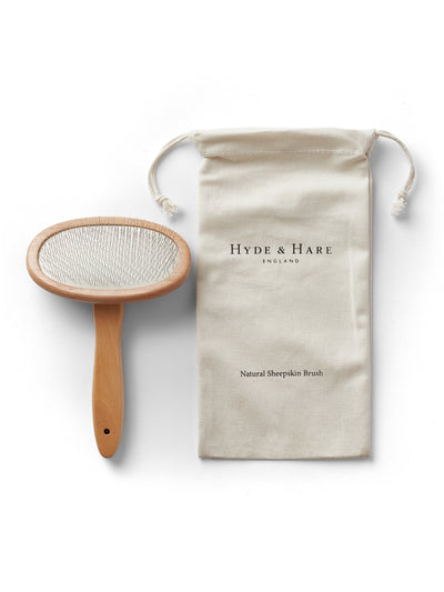 Sheepskin brush with wooden handle and branded pouch on a white background