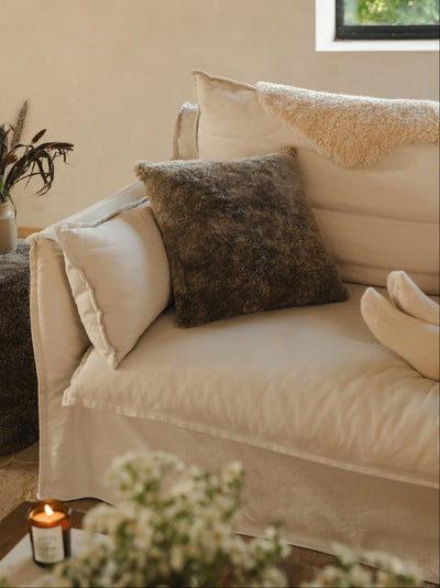 Beige sofa with sheepskin cushions in a cozy living room setting.