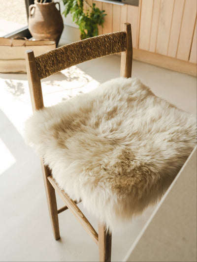 Wooden chair with a sheepskin seat on a light-colored floor